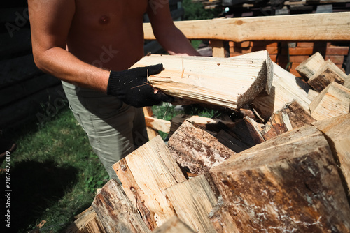 Foto Man stacking chopped firewood into wooden crate outdoors in backyard