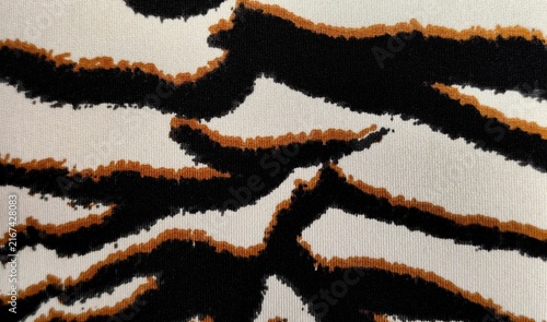 Obraz na płótnie Background view of a tiger-striped animal print pattern with bold dark brown and black wavy stripes, warm ochre and rust-orange accents, and a light cream or off-white background