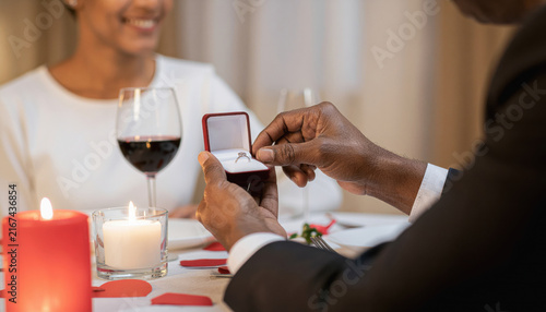 Romantic couple sharing engagement ring during candlelit dinner