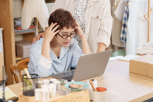 Canvas Print Adult asian daughter stressed at desk, senior mother rubs shoulder, offer comfor