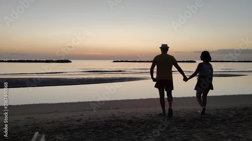 A couple in love embrace each other while waiting for the sunrise over the sea