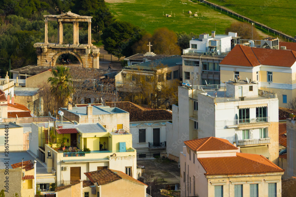 Fototapeta premium A high-angle view of the historic Arch of Hadrian in Athens, Greece, standing amidst the city's urban rooftops and residential buildings near the Acropolis.