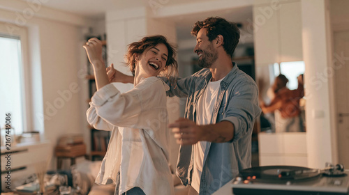 Happy couple dancing and laughing together at home, enjoying music from a turntable in their living room