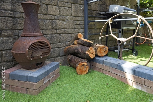 Konstfotografi A charming outdoor setting features a rusty metal chiminea, stacked firewood, an