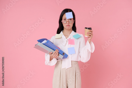 Fotografie Asian businesswoman holding folders and coffee with sticky notes expressing work overload burnout deadline pressure multitasking stress low energy and need for workplace balance