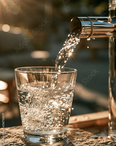 Water flows into a glass from a modern public water dispenser