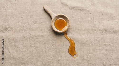 Golden organic honey dripping from wooden spoon, natural liquid honey on textured stone surface, rustic culinary ingredient isolated PNG with Transparent Background
