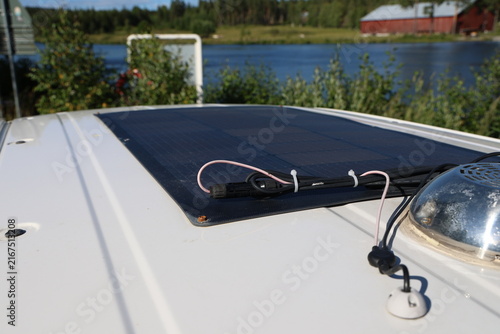 Close-up photo of a flexible solar panel installed on the roof of a white camper van.