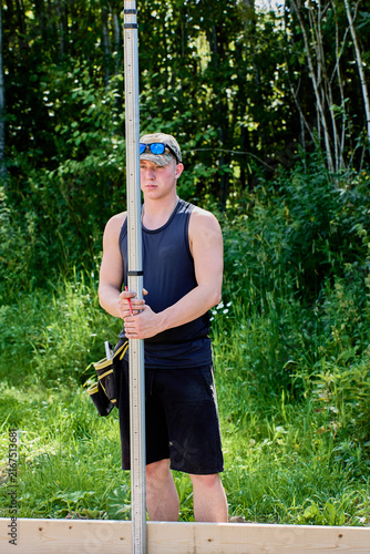 Surveying rod is held upright by field technician during precise site measurements for construction layout and elevation assessment tasks.