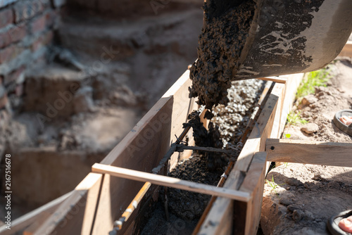 Pouring concrete into a wooden formwork for a foundation. The process of pouring fresh concrete mortar into formwork, symbolizing a construction stage, foundation, and strength