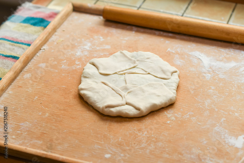 фотографія Uncooked puff pastry flatbread with filling, moldavian plachinte with layered fo