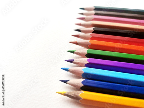 Colored pencils aligned diagonally on white paper surface