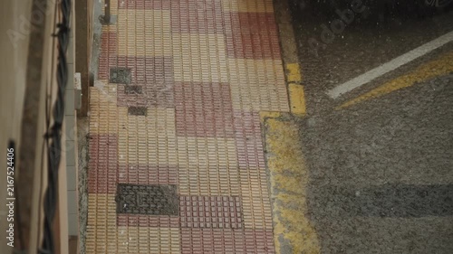 Water pours in powerful stream from drain pipe onto tiled sidewalk during rainstorm in city. Urban drainage system of rainwater. Severe weather conditions during heavy rains and floods.