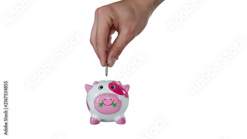 Obraz na plátně Hand dropping a coin into a small white and pink polka dot piggy bank on white b