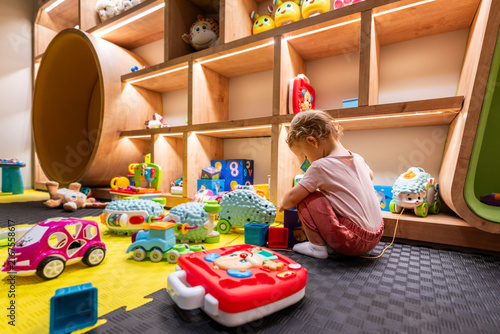 Fotografie Little girl surrounded by toys in a vibrant playroom