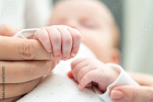 Cuadro en lienzo Mother's hand cradled by baby's tiny fingers