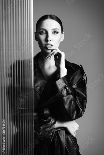 Fotografie Studio portrait of beautiful young woman standing at the plastic panel