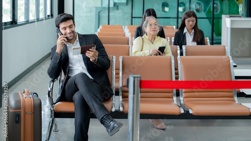 Foto A professional traveler uses a smartphone while waiting with travel documents at a modern airport terminal highlighting mobile communication and business mobility