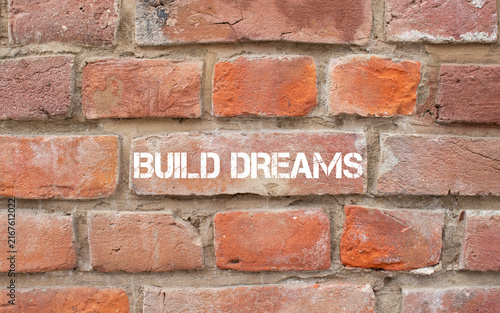 фотографія Build dreams text painted on brick wall