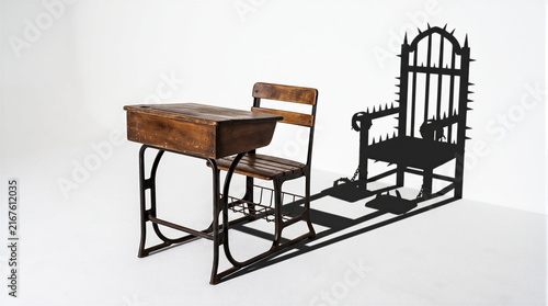 Wooden school desk casting a shadow of an electric torture chair with spikes and restraints, conceptualizing school bullying, abuse, and classroom trauma isolated on white background