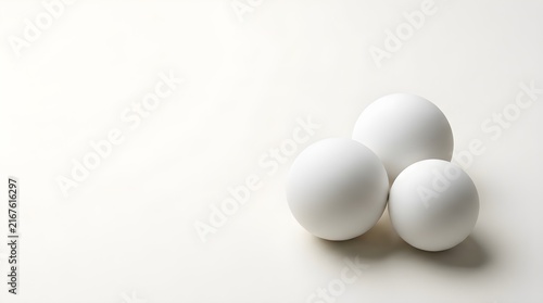 Three white eggs stacked together on neutral background for minimalist food concept