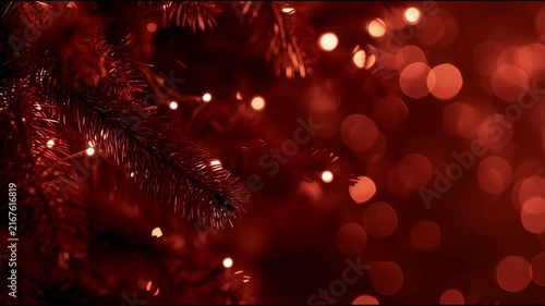 Christmas and New Year red video with animated pine branch with blurred red bokeh lights is lit by warm garland light.  