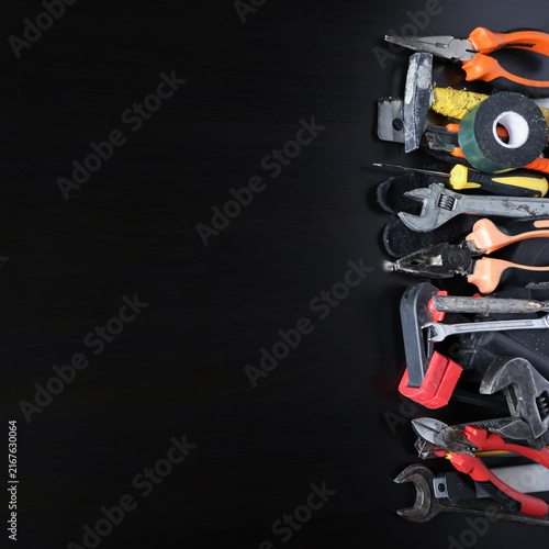 Assorted hand tools arranged along right edge on dark wooden surface, copy space for repair