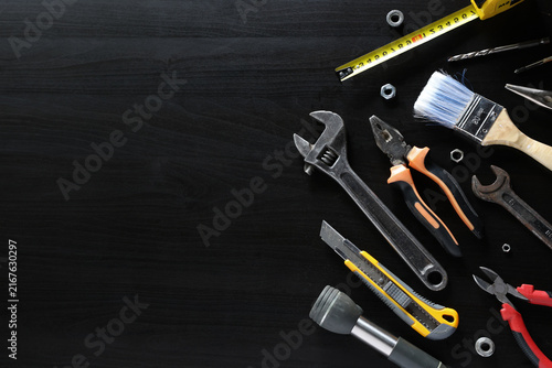 Assorted hand tools arranged on dark wooden surface with large empty copy space