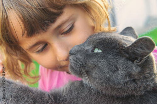 Quadro su tela A child loves a cat outdoors. Selective focus.