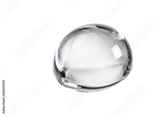 A single clear water drop falling down with soft reflections and a shiny surface for liquid textures