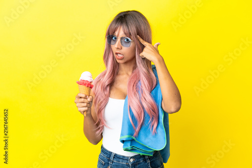 Fotografie Young mixed race woman with pink hair holding ice cream isolated on yellow backg