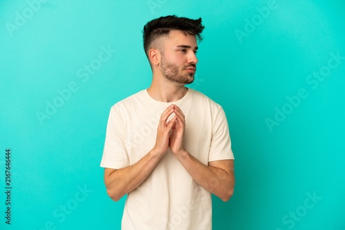 Принти на полотні Young caucasian man isolated on blue background scheming something