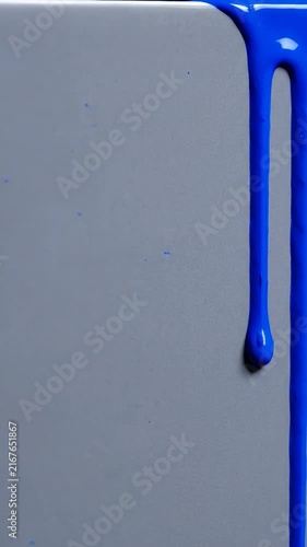 Bright Blue Paint Drip Flowing Down a Smooth Gray Surface Creating a Minimalist Artistic Abstract Background Texture