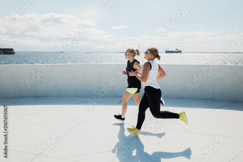 Friends enjoy a sunny afternoon jog by the sparkling waterfront with the ocean breeze invigorating their pace