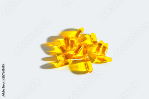 Scattered omega 3 fish oil softgels on a clean white surface with natural light creating graphic shadows, emphasizing supplements for health, nutrition, and wellness