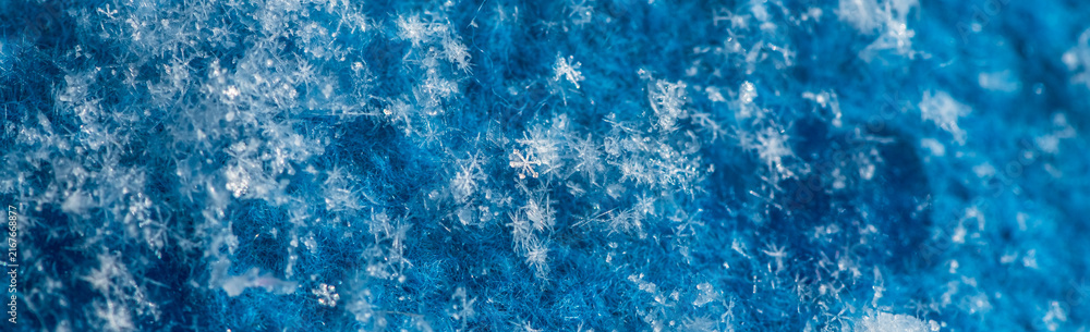 Naklejka premium Individual ice crystals forming unique patterns and creating a beautiful abstract texture on the fuzzy blue surface, showing the intricate details and cold beauty of nature during the winter season