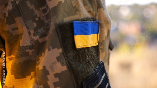 Close up of military blue-yellow chevron on shoulder of soldier at countryside. This emblem embodies the unbreakable spirit and pride of the ukrainian people. Concept of invasion resistance