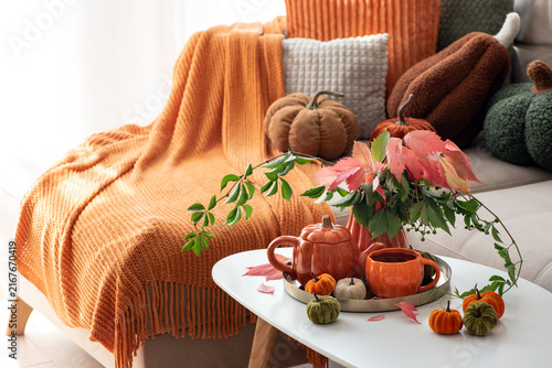 Cozy Autumn Living Room Scene with Pumpkins Blanket and Hot Beverage on Table