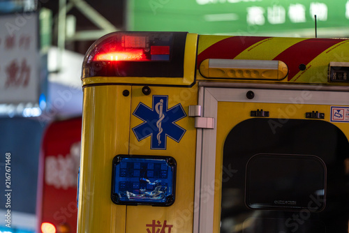 Bild auf Leinwand Tight detail view of an ambulance exterior showcasing the emergency roof beacon lit up in red, side blue flasher unit, and the blue Star of Life icon