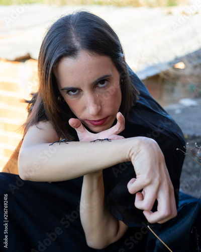 Woman Posing with Spiders on Arm in Moody Outdoor Setting