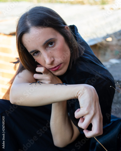 Woman Posing with Spiders on Arm in Moody Outdoor Setting