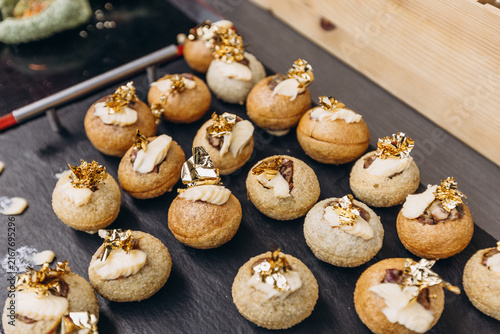 Gourmet Bites: A collection of exquisite appetizer bites, artfully arranged on a dark slate platter, showcasing delicate pastries topped with savory fillings and golden garnishes.