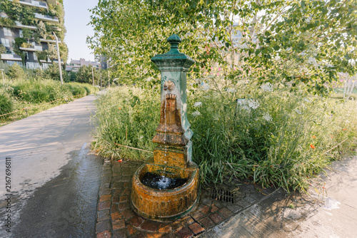 Foto Milan, Italy - May 25, 2026: Vintage water fountain surrounded by greenery on a