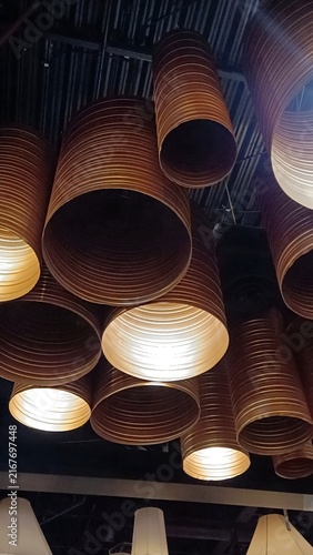 Obraz na plátně Vertical low angle shot of modern industrial ceiling lamps made of bronze corrugated pipes