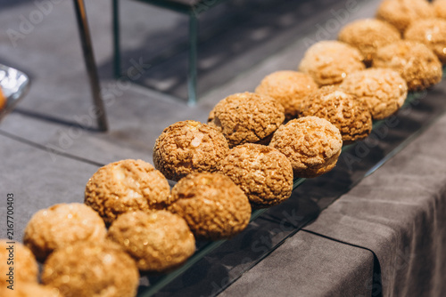 Foto Golden Puffs: A delectable line-up of golden-brown, crisp pastry puffs, elegantly displayed on a glass shelf, inviting indulgence and culinary delight