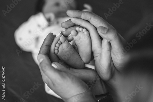 Canvastavla Tiny Toes, Infinite Love: A tender moment captured as gentle hands cradle a newborn's delicate feet, symbolizing the start of a precious journey and the boundless love of family
