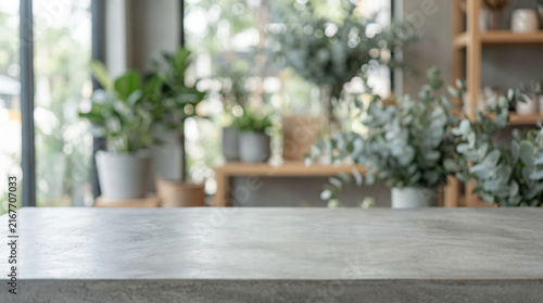 Empty grey concrete tabletop for product display against blurred background of modern room with green potted plants and copy space