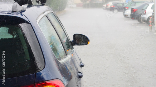 Dark Blue Car In Heavy Rainstorm On Wet Street With Flashing Mirror Light