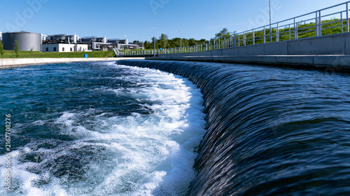 Clean water flowing over a concrete weir in a modern industrial water treatment plant under bright daylight. Perfect for environmental conservation and municipal infrastructure.