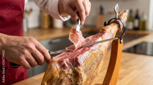A skilled person using a knife to carve delicate slices of serrano ham.